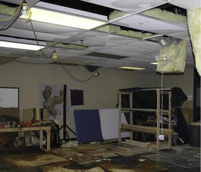 water damaged, hanging ceiling tiles, debris and water on floor, art on the walls